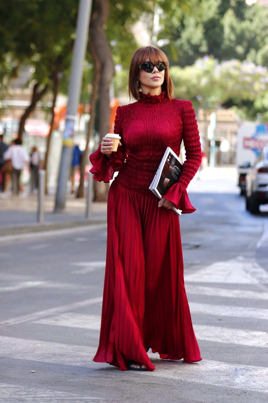 Mujer con conjunto burdeos de cuerpo plisado, hombros estructurados y pantalón palazzo.