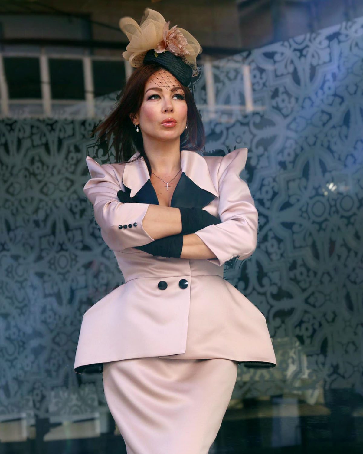Mujer con conjunto rosa de chaqueta peplum estructurada, falda recta y tocado floral.