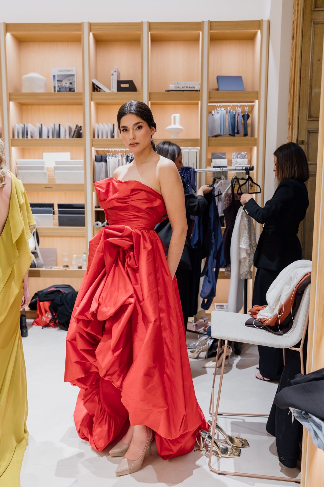 Mujer con vestido rojo palabra de honor, cuerpo drapeado y falda asimétrica de gran volumen.